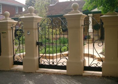 ornate-lockable-victorian-design-black-front-gate-and-fence-featuring-additional-ornate-side-panels-mounted-between-traditional-columns-with-spheres-on-top