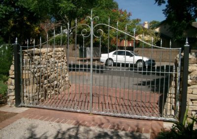 silver-painted-steel-double-driveway-steel-gates-mounted-between-a-feature-stone-wall